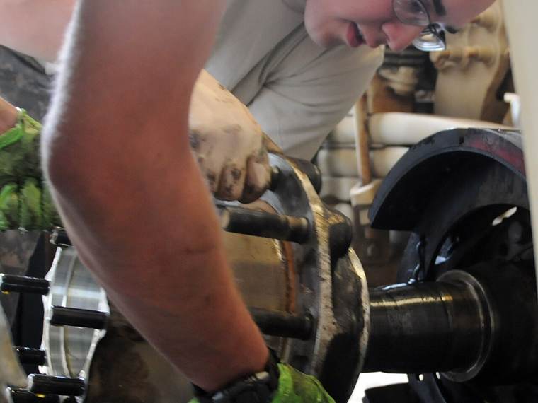 Mechanic servicing a heavy truck wheel end and brakes