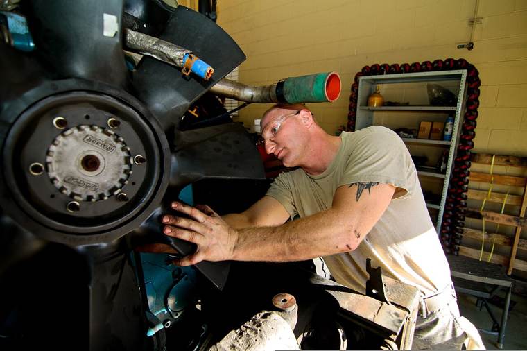Mechanic performing preventive maintenance on a heavy-duty diesel engine